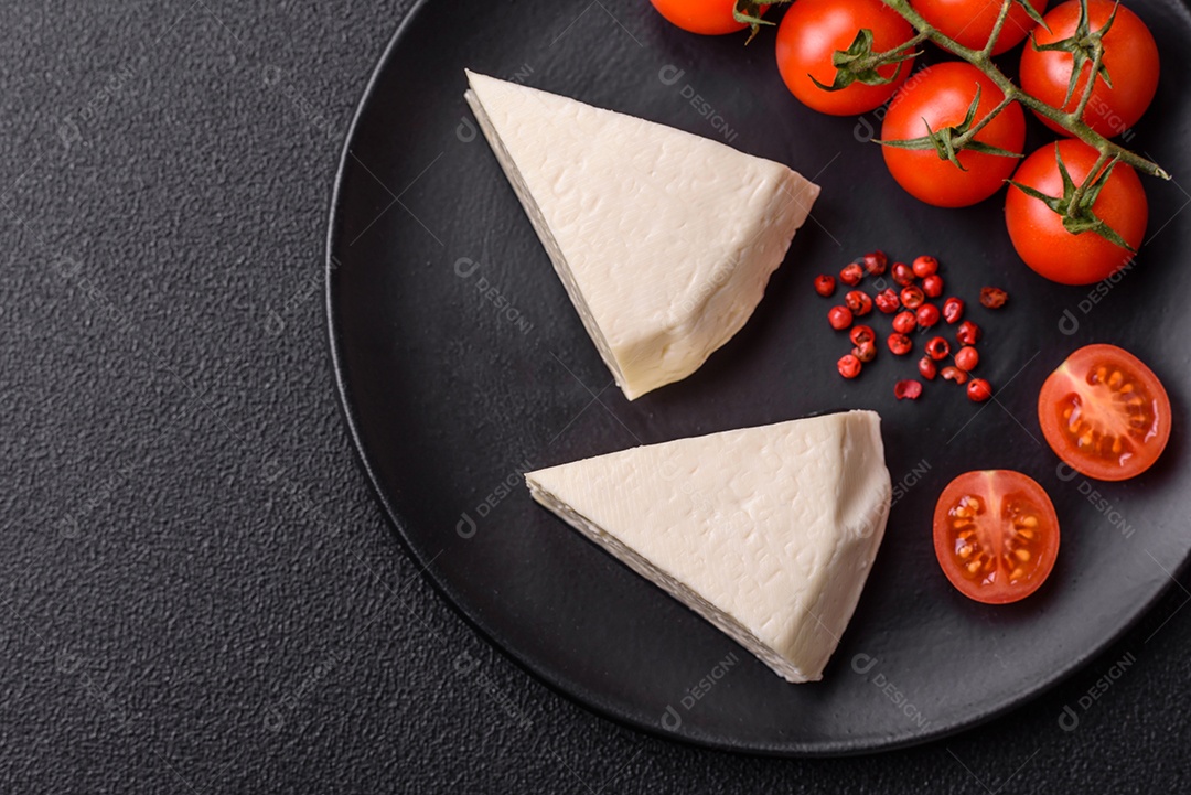 Delicioso queijo jovem branco fresco de leite de vaca ou ovelha sobre um fundo escuro de concreto