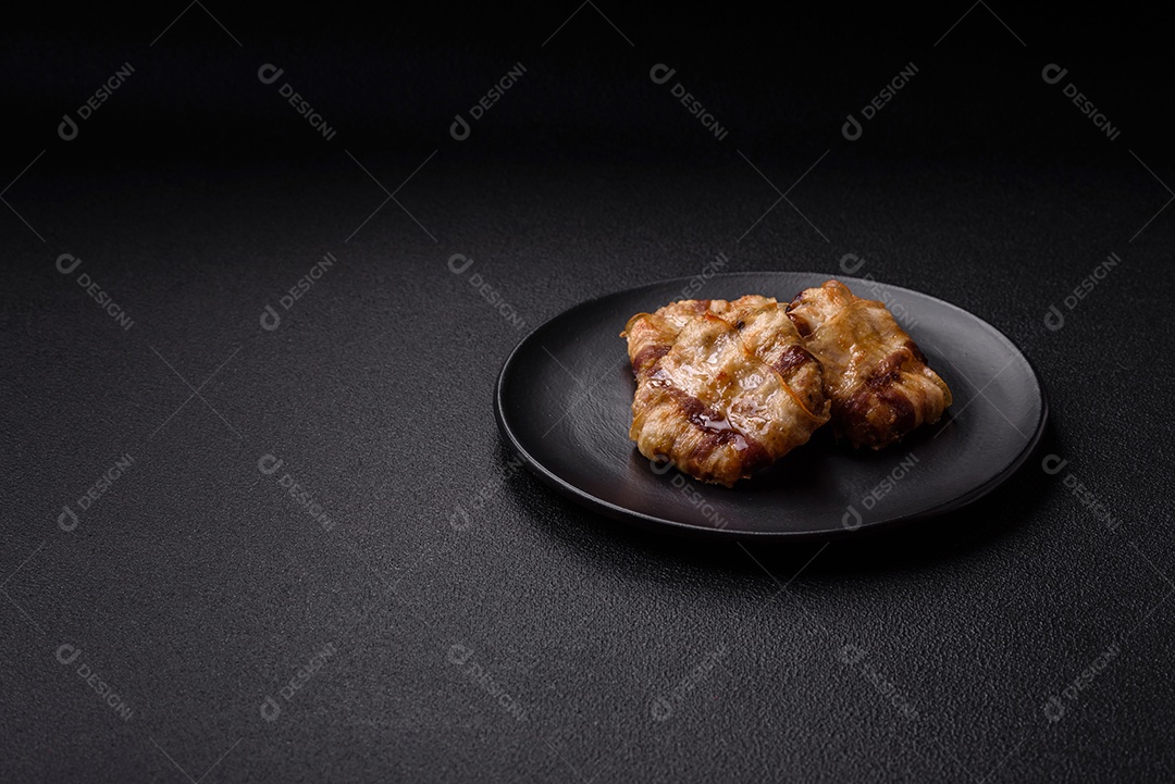 Frango picado redondo ou costeleta de porco envolta em bacon com sal, especiarias e ervas sobre um fundo escuro de concreto