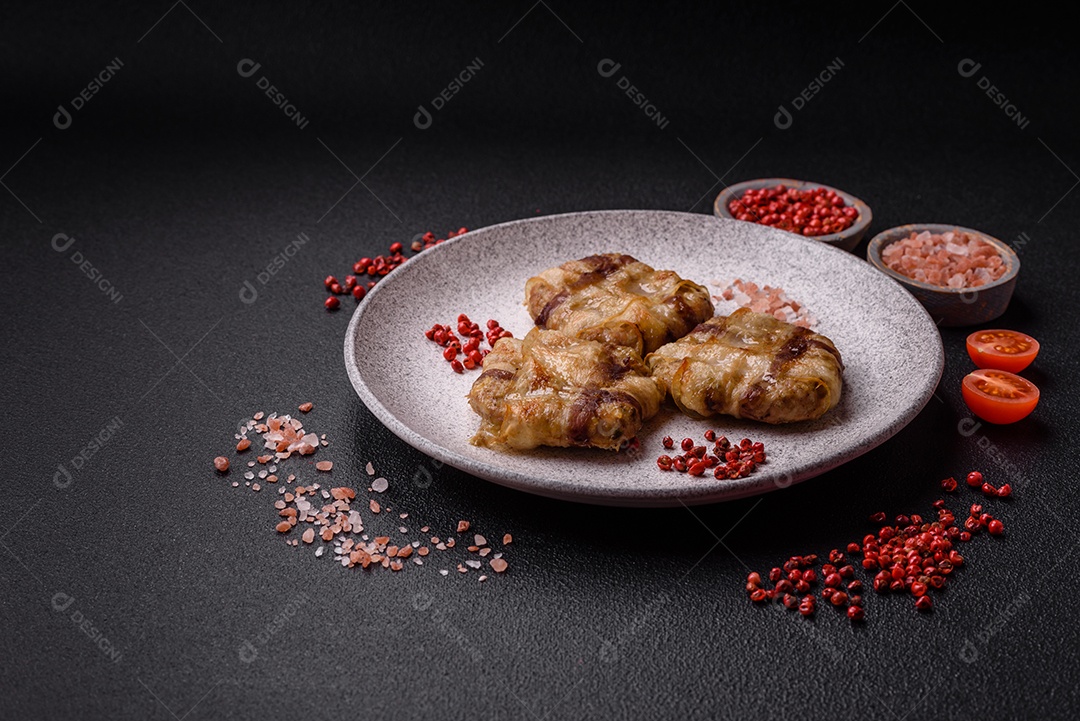 Frango picado redondo ou costeleta de porco envolta em bacon com sal, especiarias e ervas sobre um fundo escuro de concreto