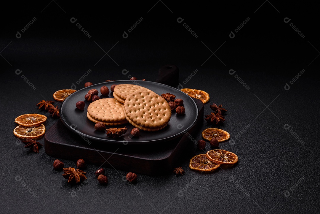 Biscoitos redondos pontilhados com creme em um fundo escuro de concreto. Doces no café da manhã