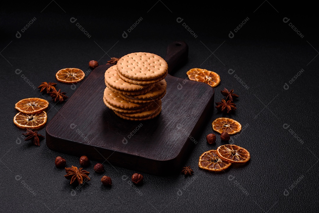 Biscoitos redondos pontilhados com creme em um fundo escuro de concreto. Doces no café da manhã