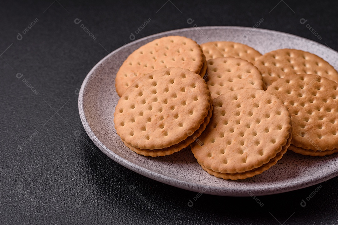 Biscoitos redondos pontilhados com creme em um fundo escuro de concreto. Doces no café da manhã