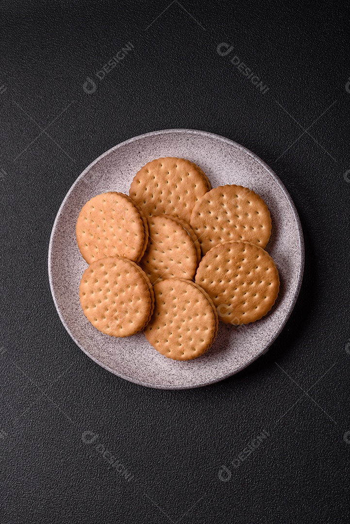 Biscoitos redondos pontilhados com creme em um fundo escuro de concreto. Doces no café da manhã