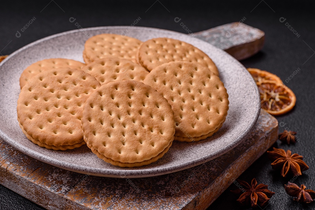 Biscoitos redondos pontilhados com creme em um fundo escuro de concreto. Doces no café da manhã