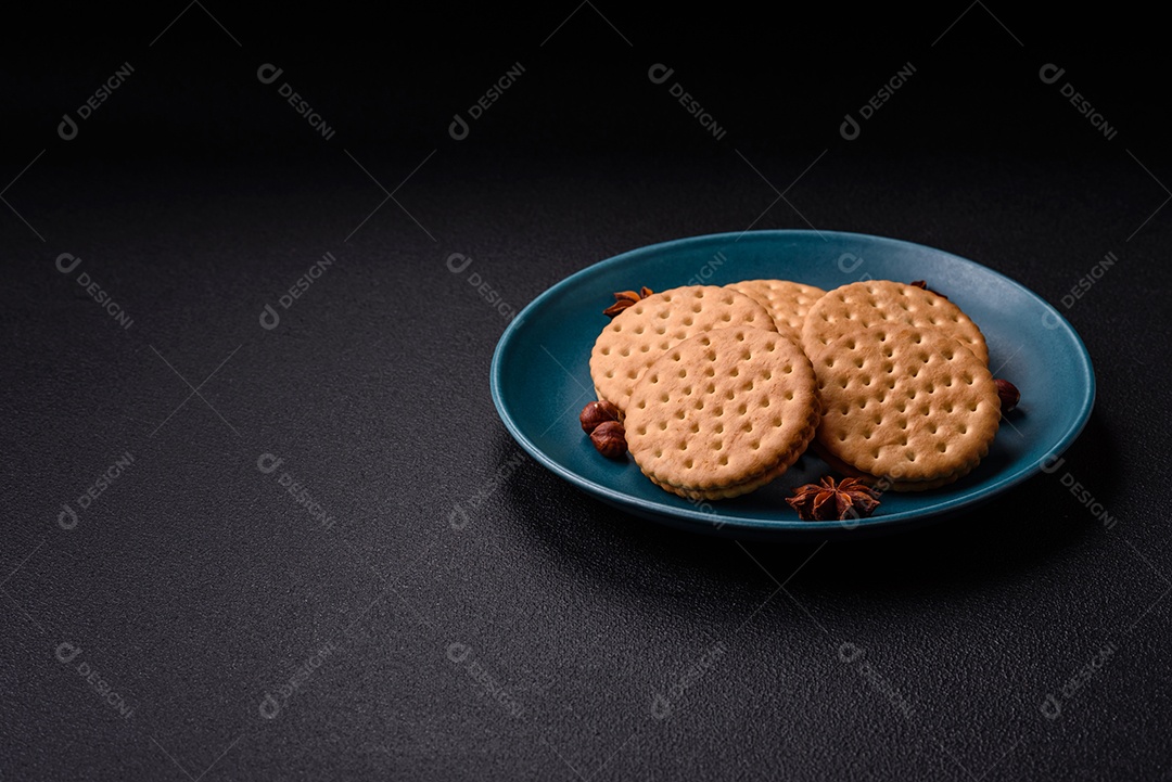 Biscoitos redondos pontilhados com creme em um fundo escuro de concreto. Doces no café da manhã