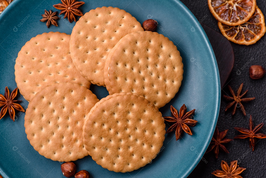 Biscoitos redondos pontilhados com creme em um fundo escuro de concreto. Doces no café da manhã