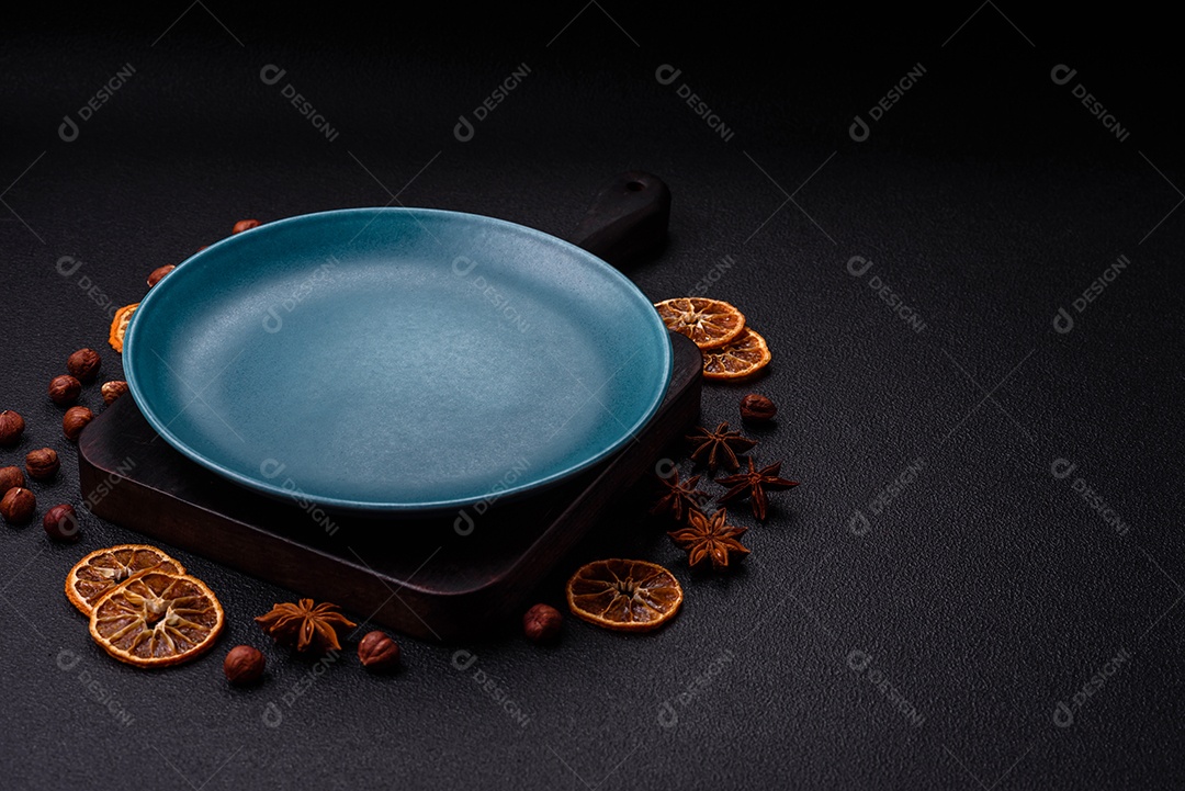 Placa redonda de cerâmica vazia em fundo de concreto texturizado escuro. Talheres, preparação para o jantar