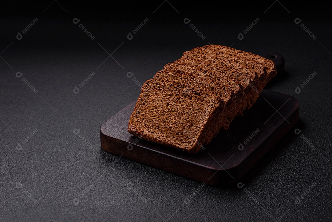 Delicioso pão integral com sementes e grãos cortados em fatias sobre um fundo de concreto texturizado