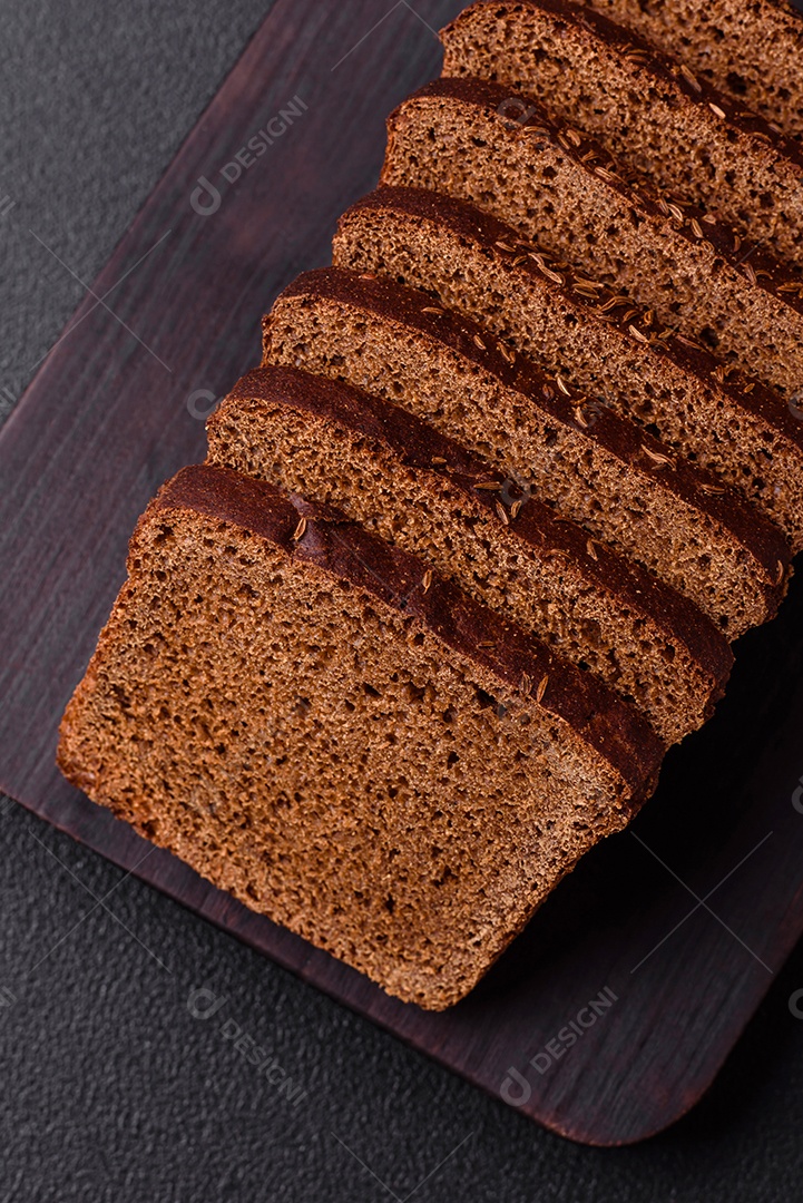 Delicioso pão integral com sementes e grãos cortados em fatias sobre um fundo de concreto texturizado