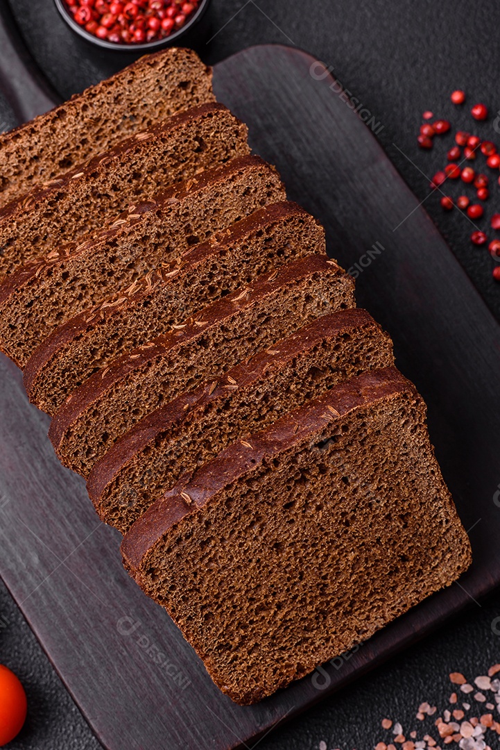 Delicioso pão integral com sementes e grãos cortados em fatias sobre um fundo de concreto texturizado