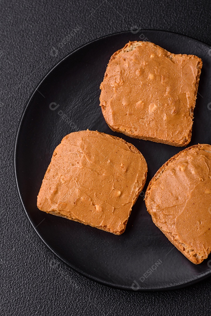 Delicioso sanduíche saudável com pão torrado e manteiga de amendoim em um fundo de concreto texturizado