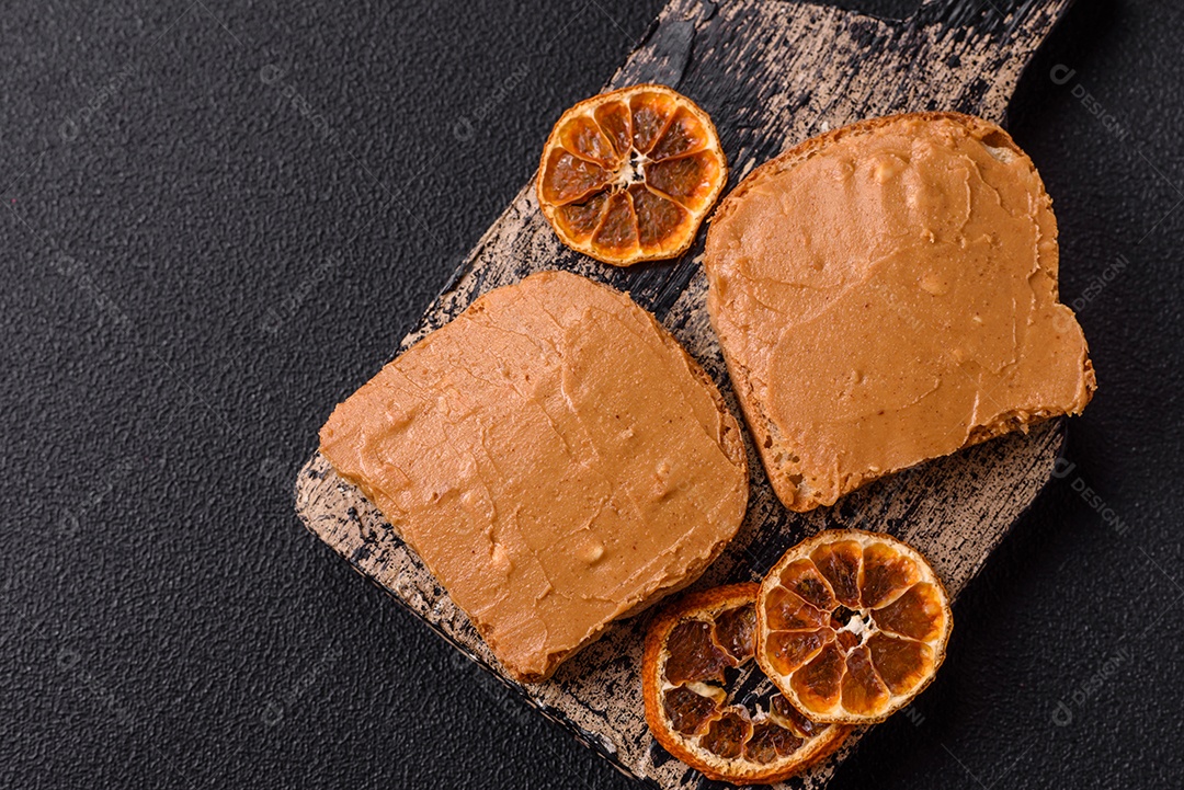 Delicioso sanduíche saudável com pão torrado e manteiga de amendoim em um fundo de concreto texturizado