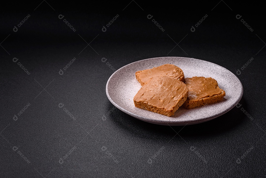 Delicioso sanduíche saudável com pão torrado e manteiga de amendoim em um fundo de concreto texturizado