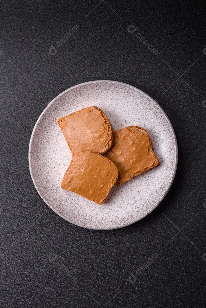 Delicioso sanduíche saudável com pão torrado e manteiga de amendoim em um fundo de concreto texturizado