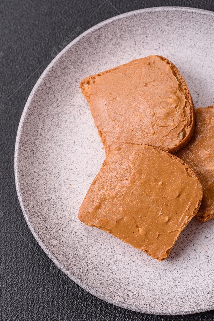 Delicioso sanduíche saudável com pão torrado e manteiga de amendoim em um fundo de concreto texturizado