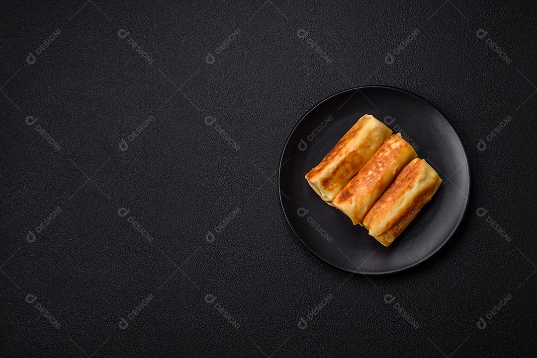 Deliciosas panquecas fritas com recheio roladas sobre um fundo escuro de concreto. Delicioso café da manhã nutritivo