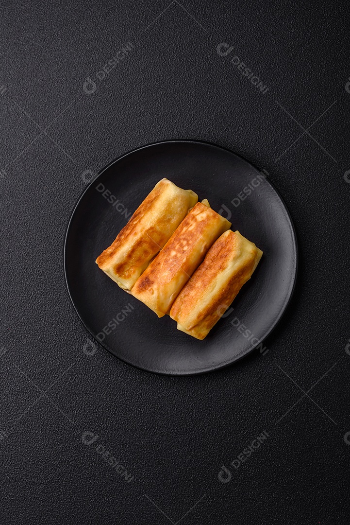 Deliciosas panquecas fritas com recheio roladas sobre um fundo escuro de concreto. Delicioso café da manhã nutritivo