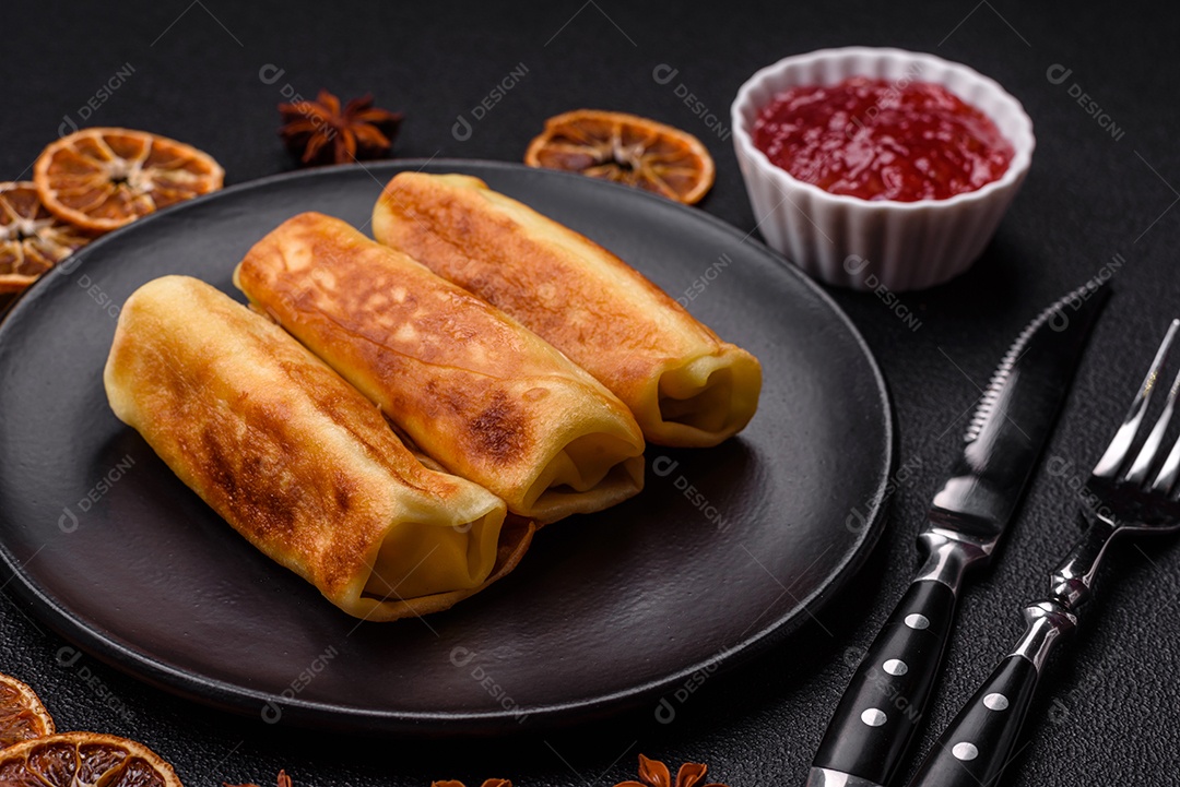 Deliciosas panquecas fritas com recheio roladas sobre um fundo escuro de concreto. Delicioso café da manhã nutritivo