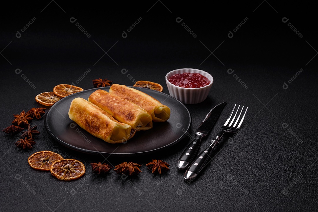 Deliciosas panquecas fritas com recheio roladas sobre um fundo escuro de concreto. Delicioso café da manhã nutritivo