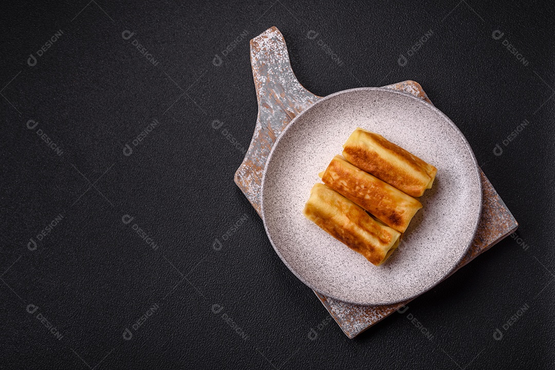 Deliciosas panquecas fritas com recheio roladas sobre um fundo escuro de concreto. Delicioso café da manhã nutritivo