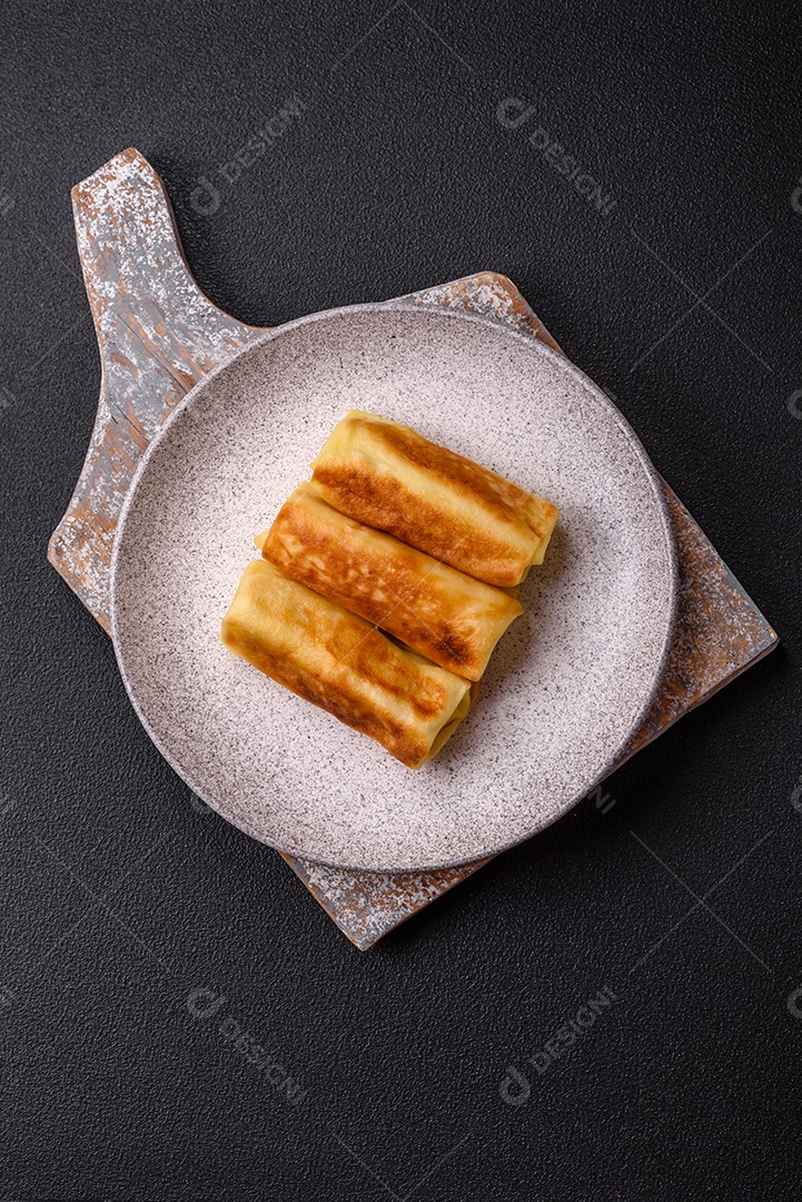 Deliciosas panquecas fritas com recheio roladas sobre um fundo escuro de concreto. Delicioso café da manhã nutritivo