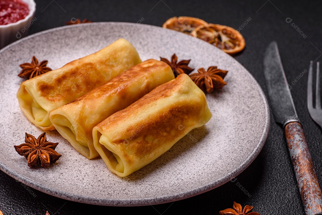 Deliciosas panquecas fritas com recheio roladas sobre um fundo escuro de concreto. Delicioso café da manhã nutritivo