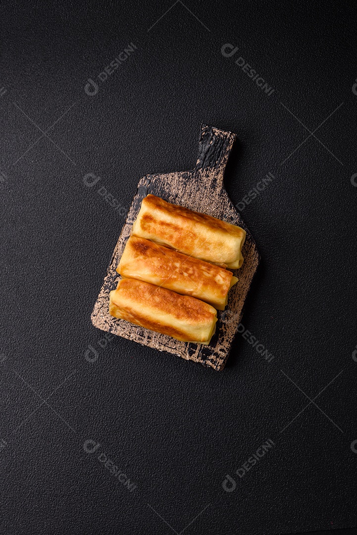 Deliciosas panquecas fritas com recheio roladas sobre um fundo escuro de concreto. Delicioso café da manhã nutritivo