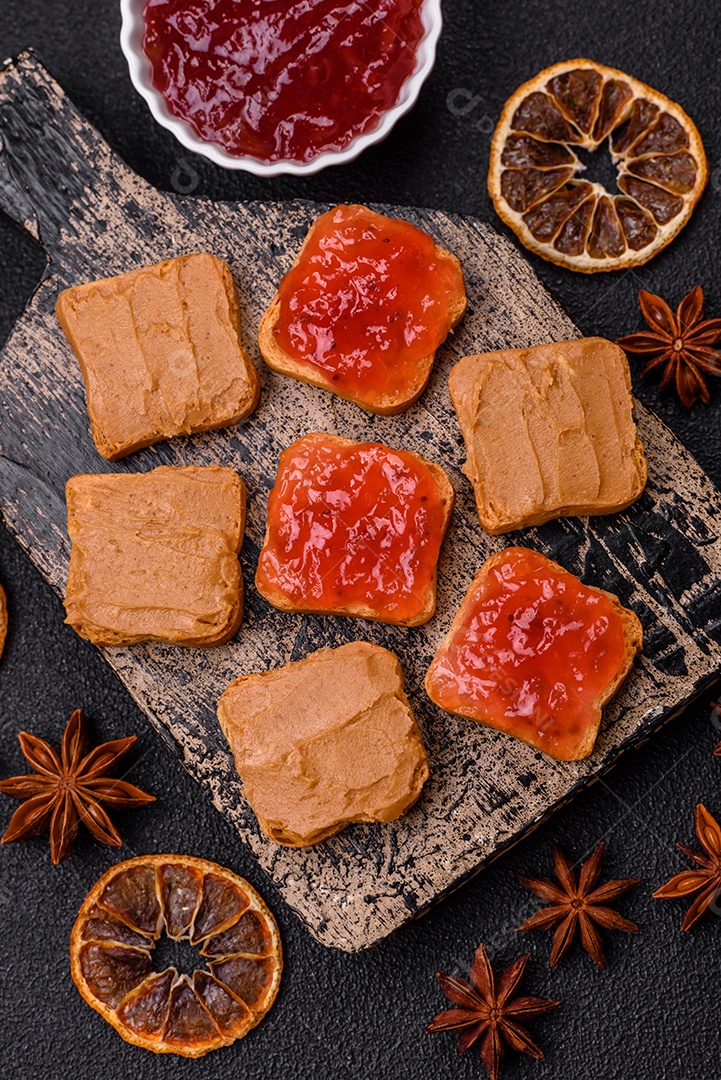 Deliciosos sanduíches nutritivos com manteiga de amendoim, geléia de morango sobre fundo escuro de concreto