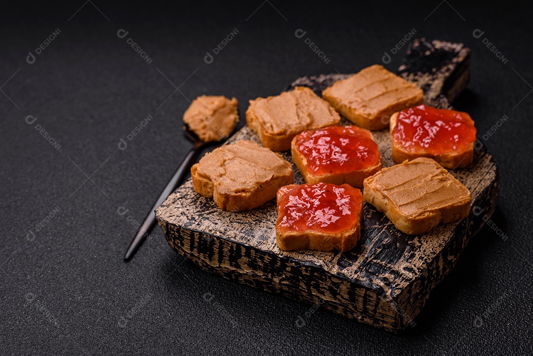 Deliciosos sanduíches nutritivos com manteiga de amendoim, geléia de morango sobre fundo escuro de concreto