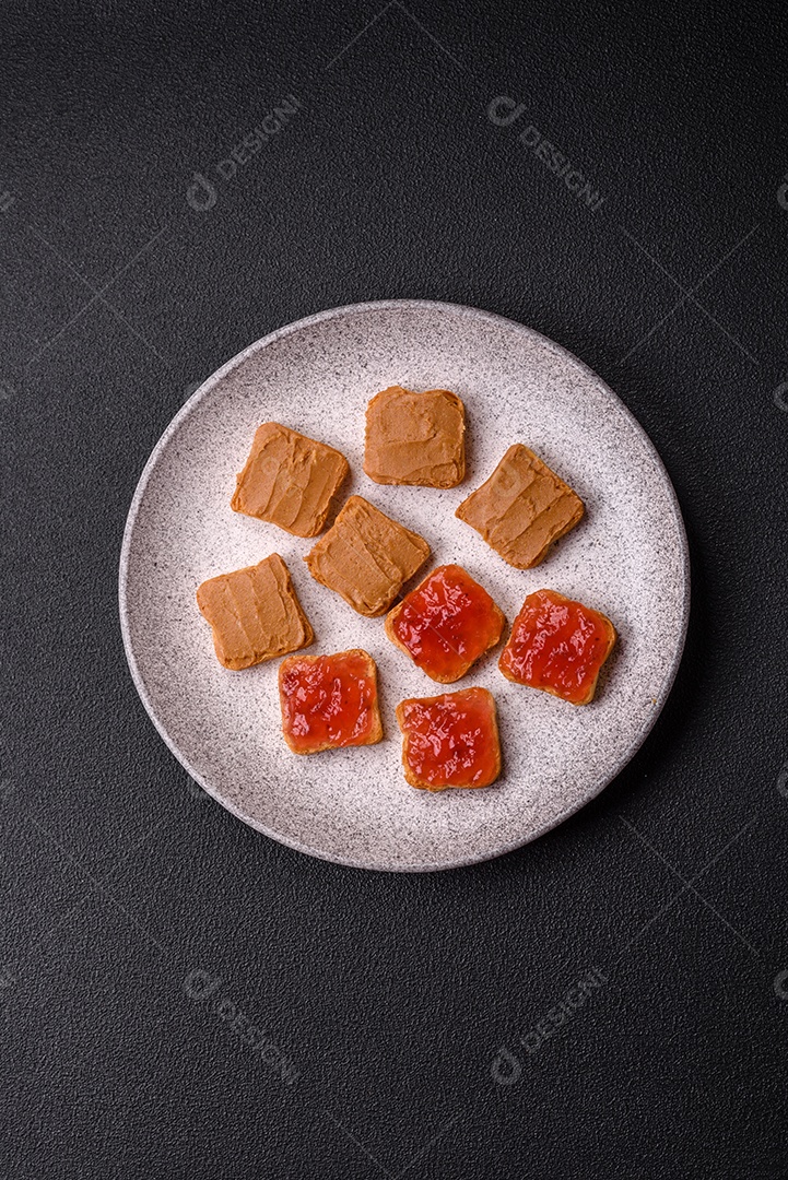 Deliciosos sanduíches nutritivos com manteiga de amendoim, geléia de morango sobre fundo escuro de concreto