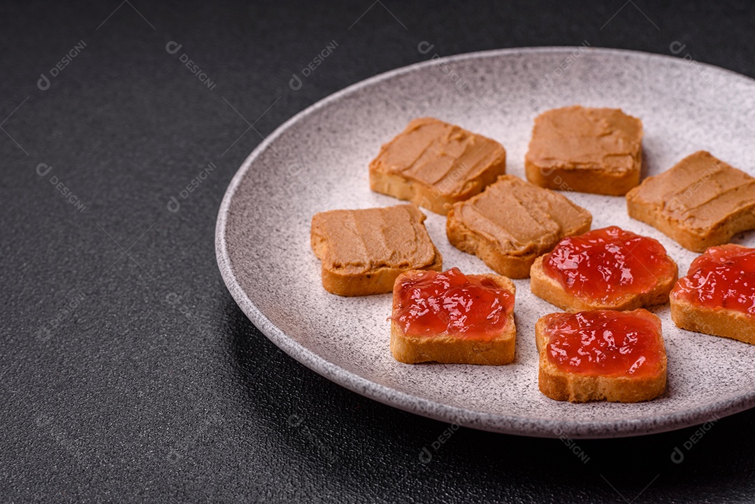 Deliciosos sanduíches nutritivos com manteiga de amendoim, geléia de morango sobre fundo escuro de concreto