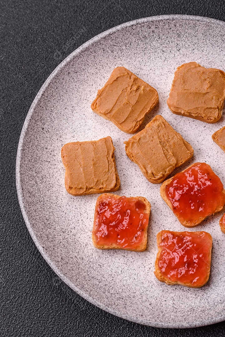 Deliciosos sanduíches nutritivos com manteiga de amendoim, geléia de morango sobre fundo escuro de concreto