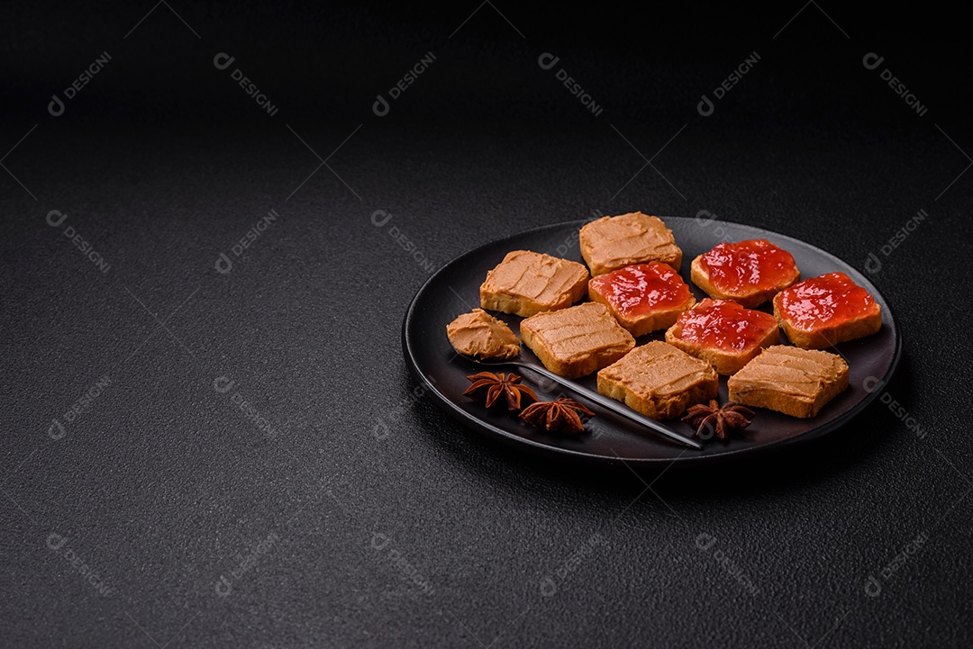 Deliciosos sanduíches nutritivos com manteiga de amendoim, geléia de morango sobre fundo escuro de concreto