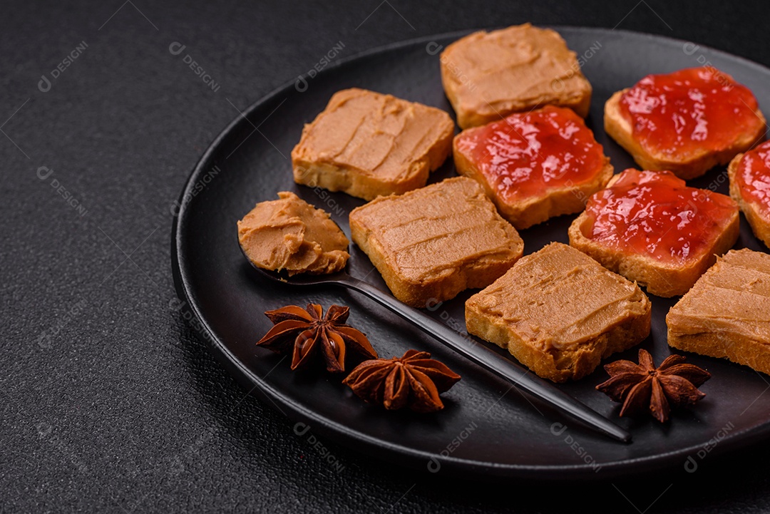 Deliciosos sanduíches nutritivos com manteiga de amendoim, geléia de morango sobre fundo escuro de concreto