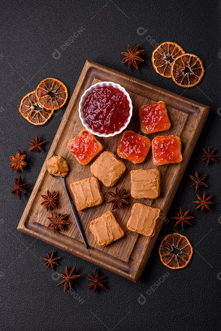 Deliciosos sanduíches nutritivos com manteiga de amendoim, geléia de morango sobre fundo escuro de concreto