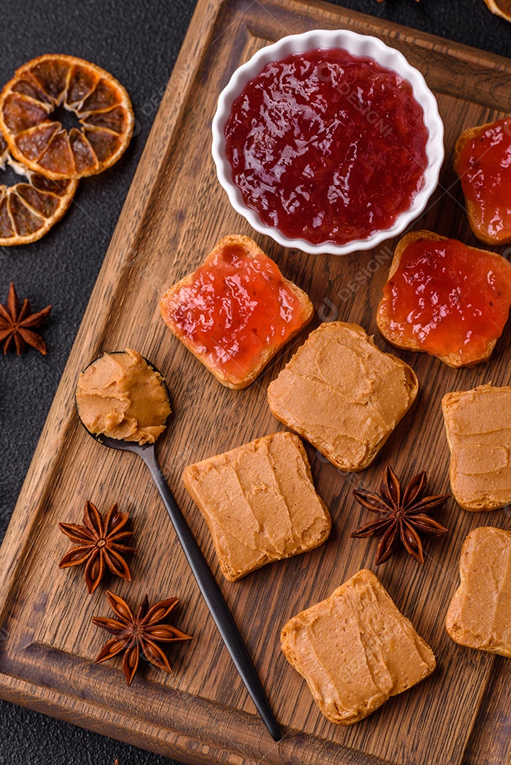 Deliciosos sanduíches nutritivos com manteiga de amendoim, geléia de morango sobre fundo escuro de concreto
