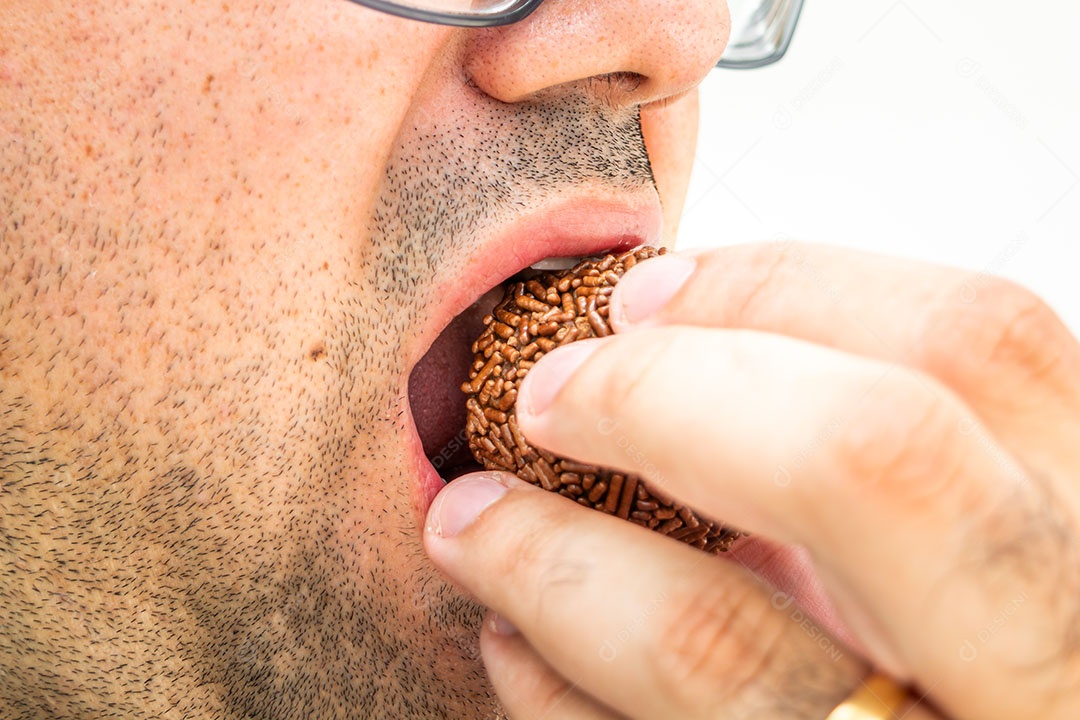 Homem com excesso de peso comendo um brigadeiro, sobremesa tradicional brasileira