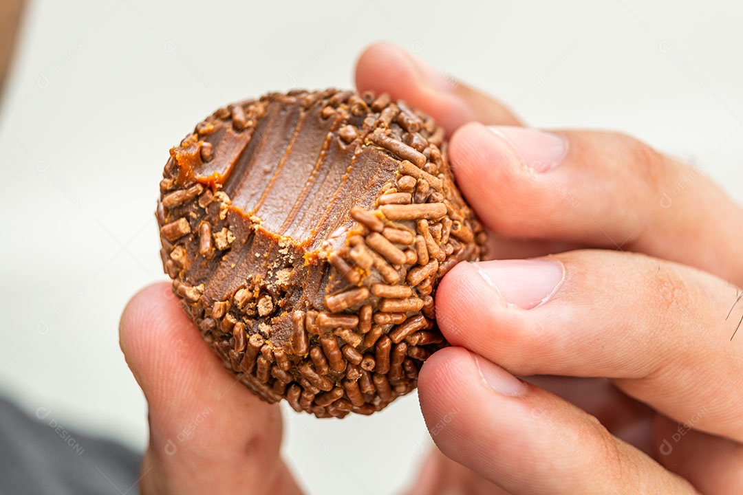 Homem com excesso de peso comendo um brigadeiro, sobremesa tradicional brasileira
