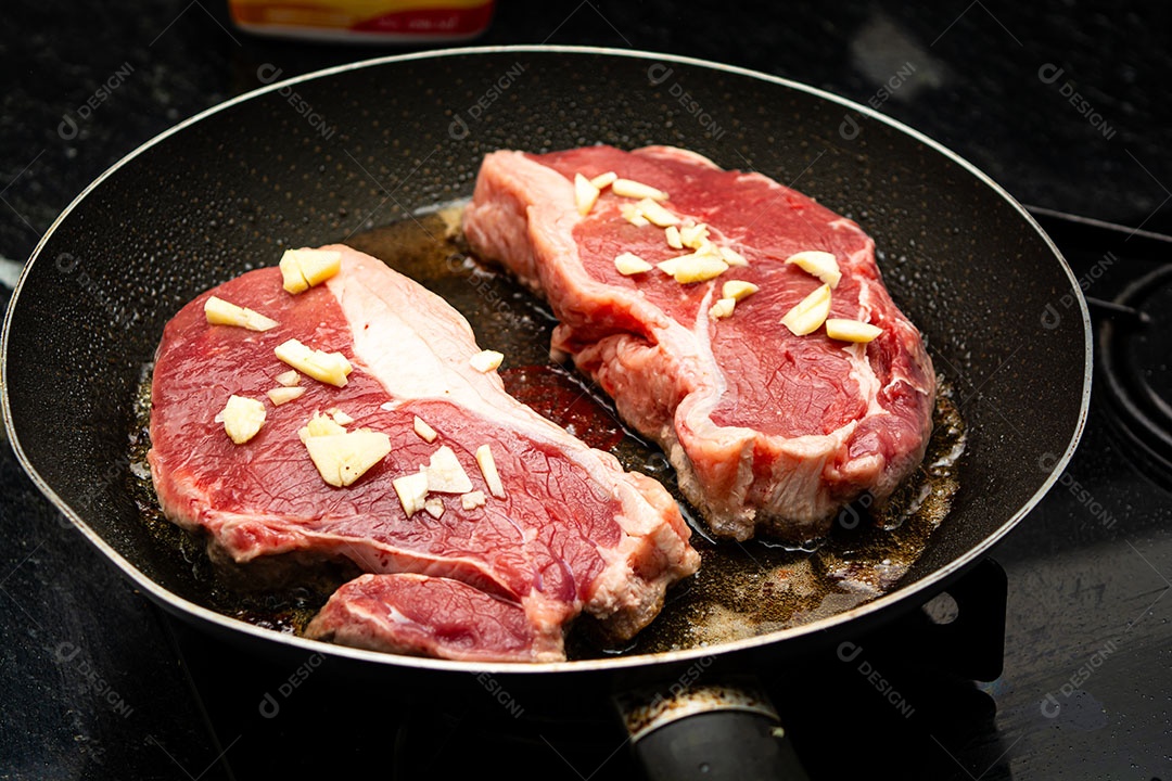 Fritando dois bifes de lombo com alho para o jantar