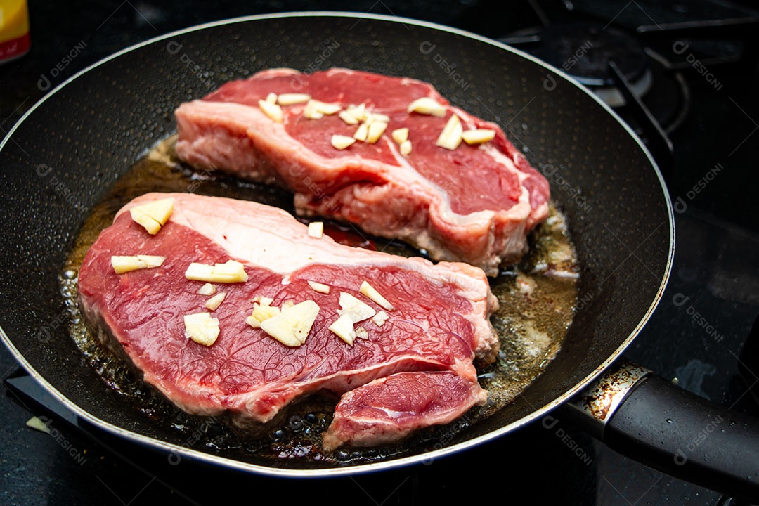 Fritando dois bifes de lombo com alho para o jantar