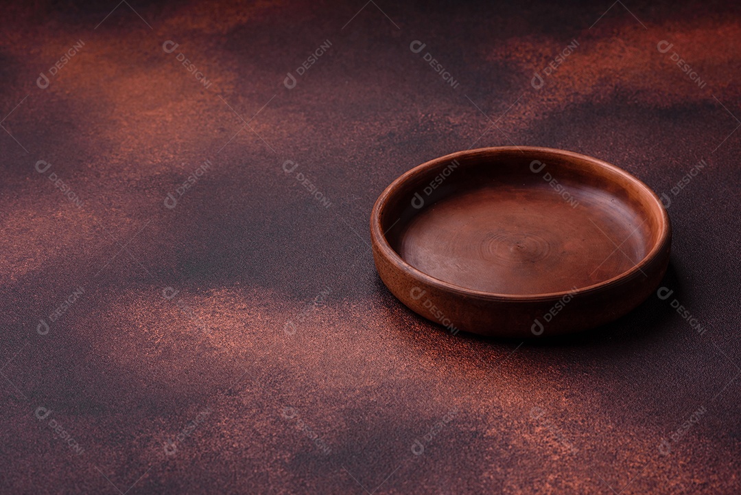 Placa redonda de cerâmica vazia em fundo de concreto texturizado escuro. Talheres, preparação para o jantar