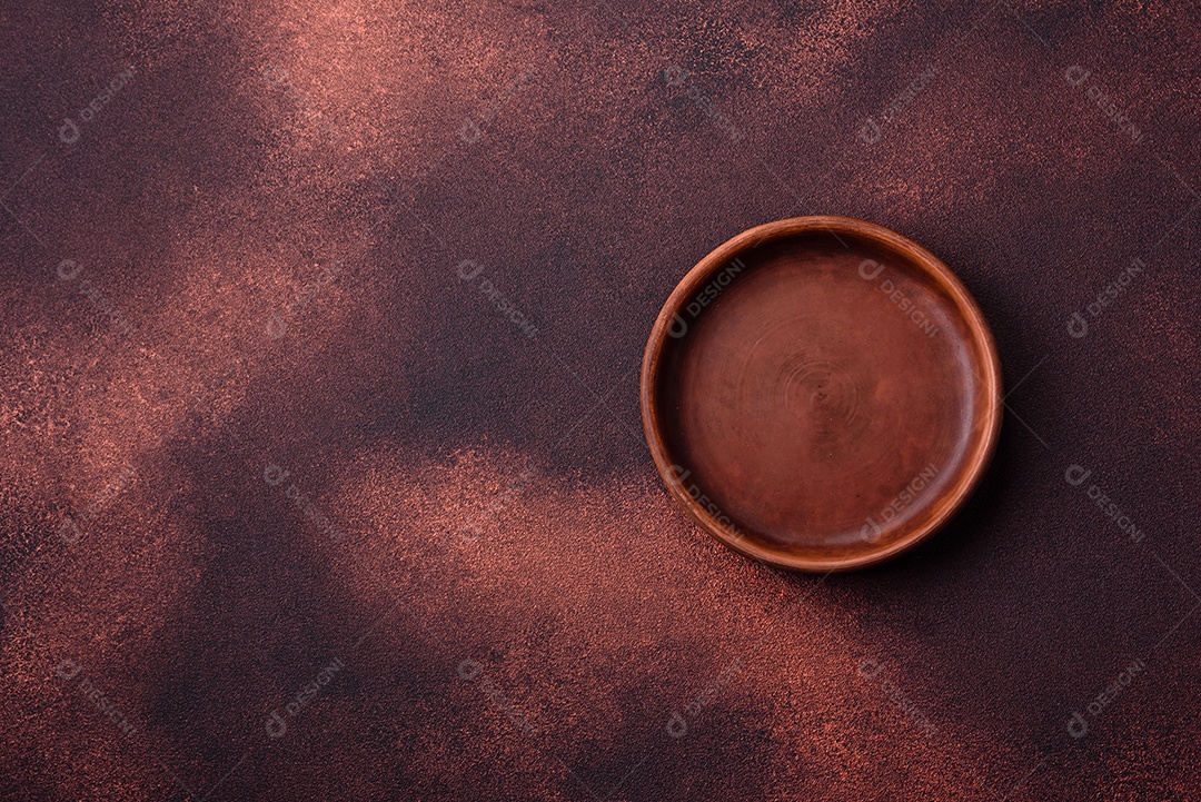 Placa redonda de cerâmica vazia em fundo de concreto texturizado escuro. Talheres, preparação para o jantar