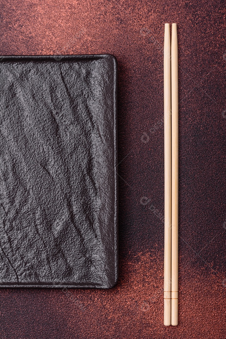 Placa cerâmica quadrada preta vazia em fundo de concreto escuro. Cozinhar comida asiática