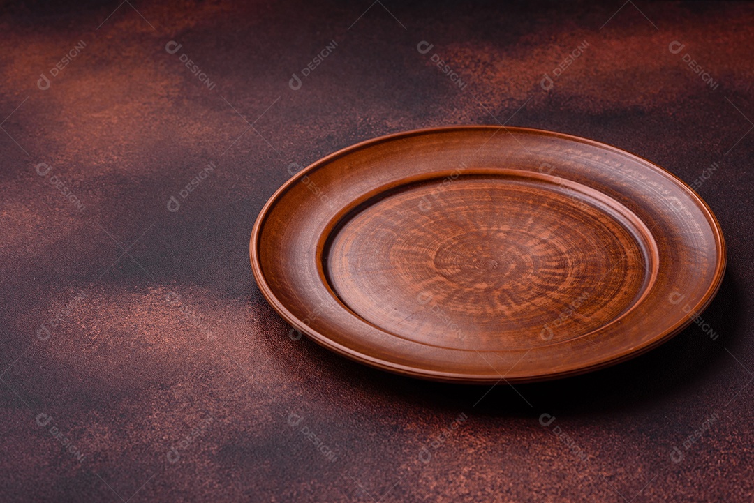 Placa redonda de cerâmica vazia em fundo de concreto texturizado escuro. Talheres, preparação para o jantar