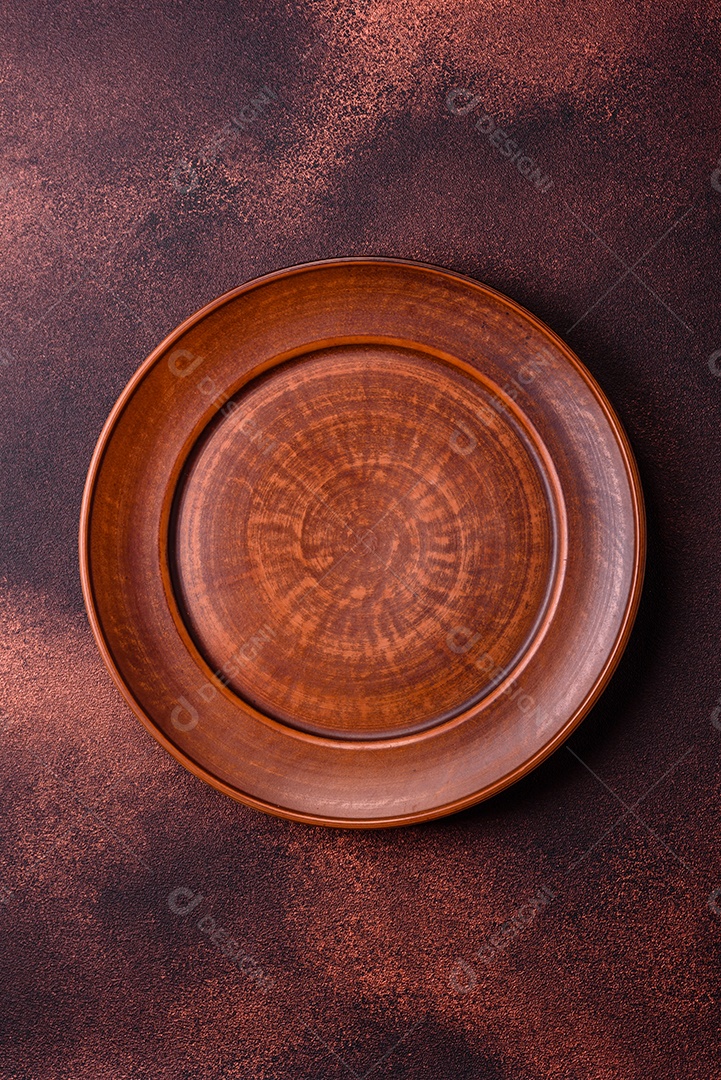 Placa redonda de cerâmica vazia em fundo de concreto texturizado escuro. Talheres, preparação para o jantar