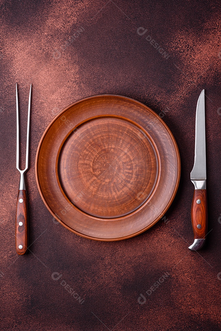 Placa redonda de cerâmica vazia em fundo de concreto texturizado escuro. Talheres, preparação para o jantar