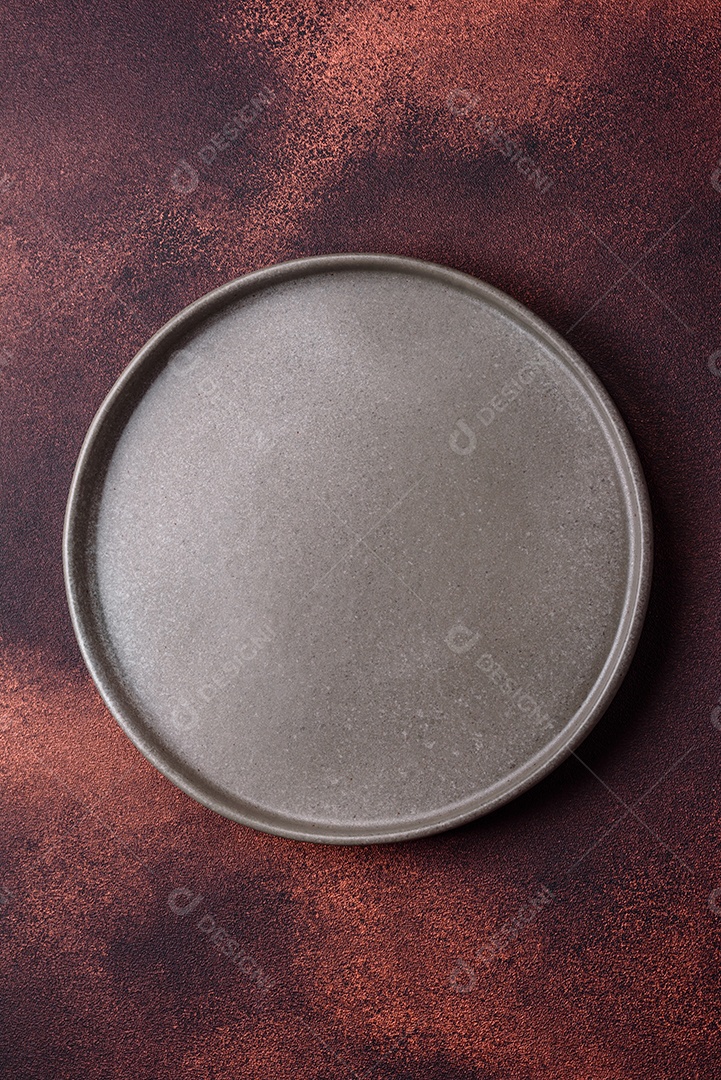 Placa redonda de cerâmica vazia em fundo de concreto texturizado escuro. Talheres, preparação para o jantar