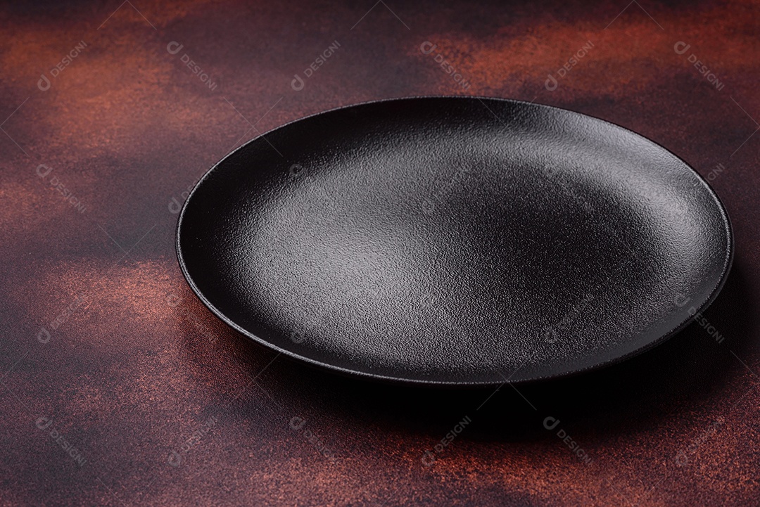 Placa redonda de cerâmica vazia em fundo de concreto texturizado escuro. Talheres, preparação para o jantar