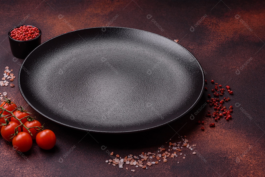 Placa redonda de cerâmica vazia em fundo de concreto texturizado escuro. Talheres, preparação para o jantar