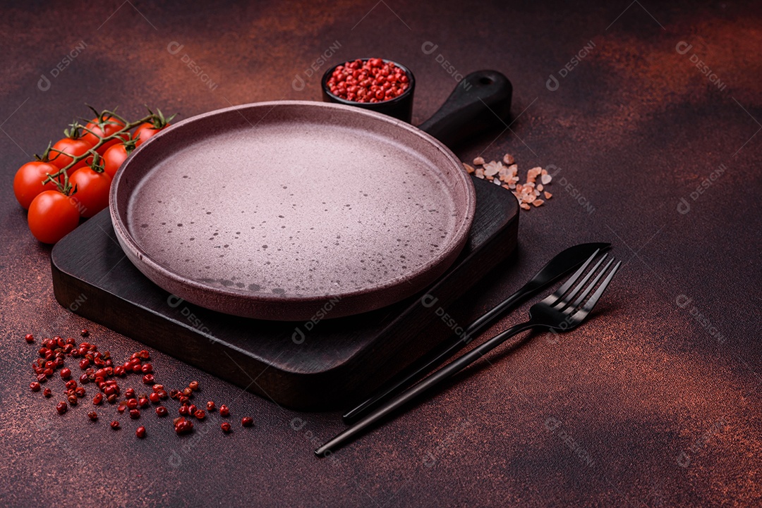 Placa redonda de cerâmica vazia em fundo de concreto texturizado escuro. Talheres, preparação para o jantar